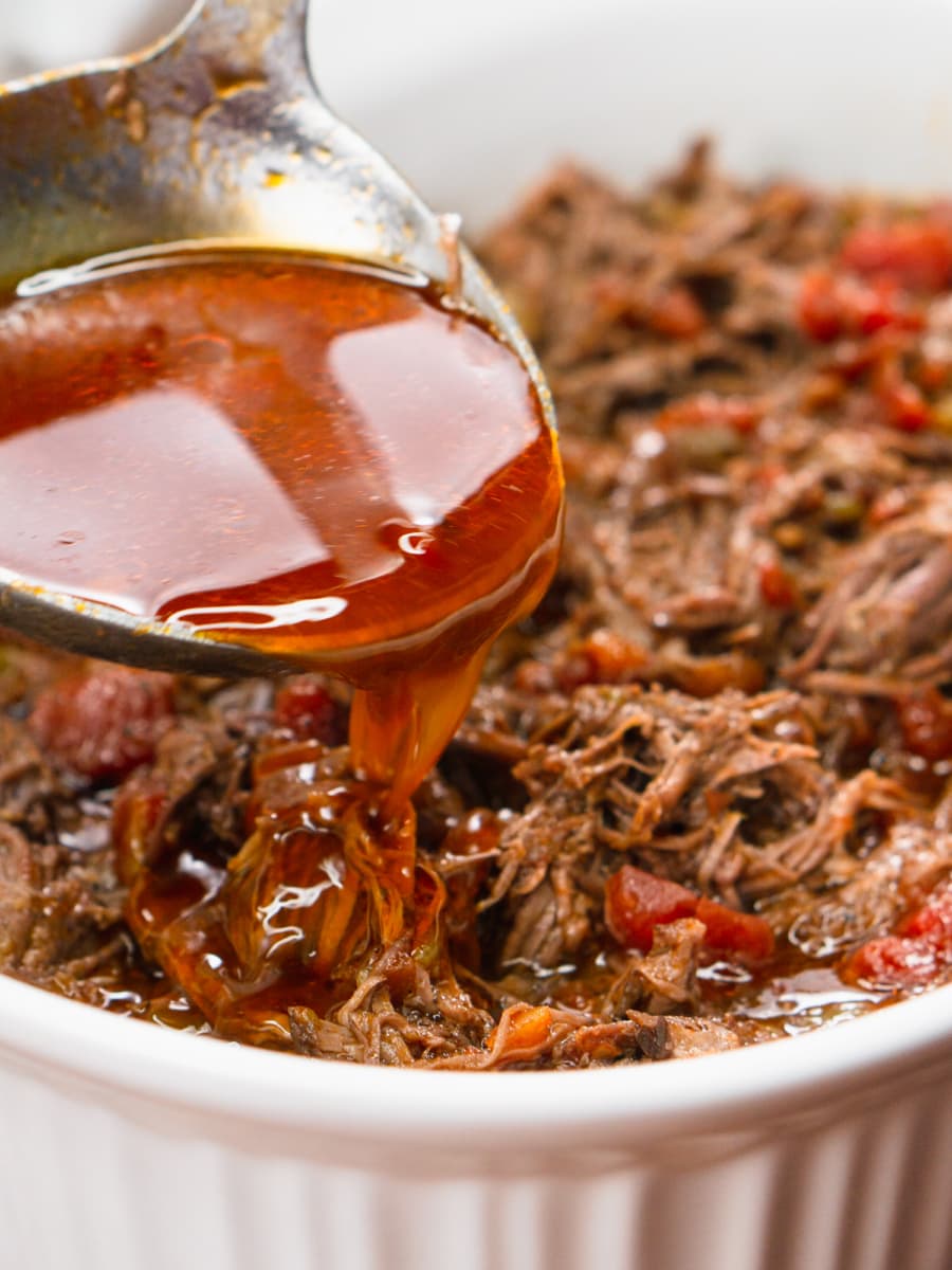 pouring liquid over slow cooker carne mechada