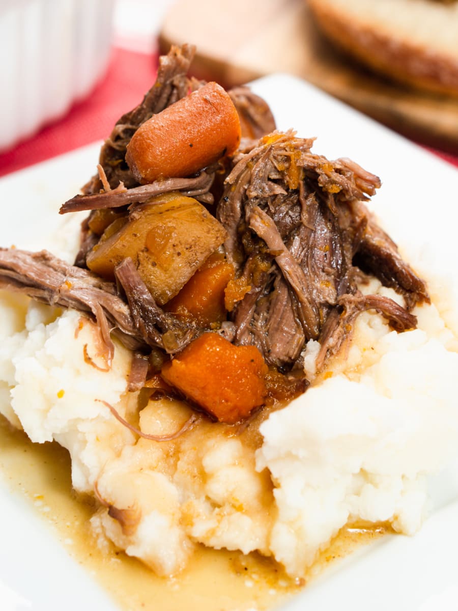 a plate of slow cooker pot roast served over mashed potatoes