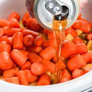 pouring a beer over the pot roast ingredients in the slow cooker