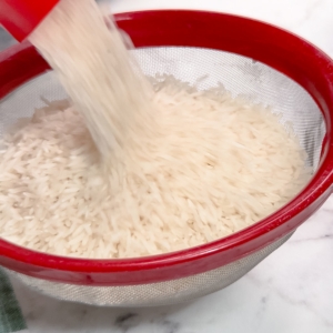 adding rice to a mesh strainer