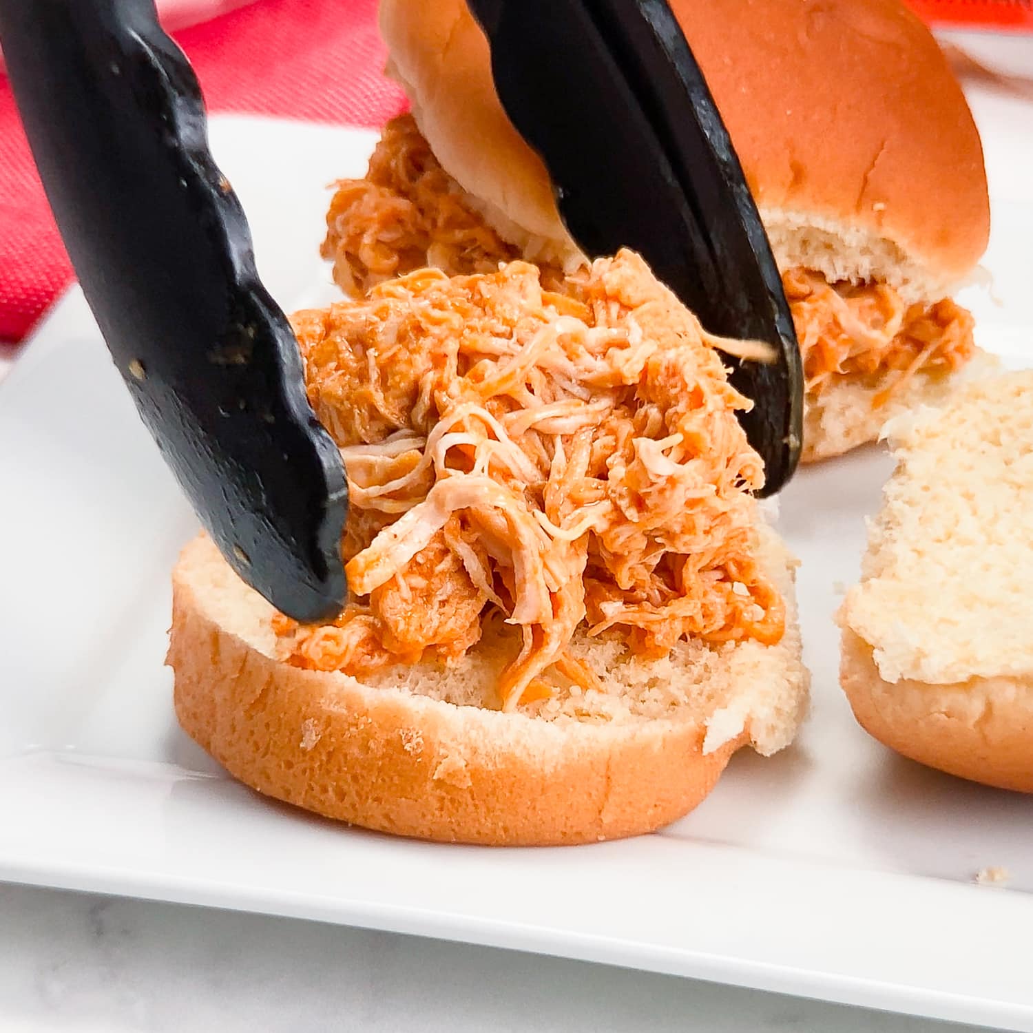 adding shredded buffalo chicken to a slider bun