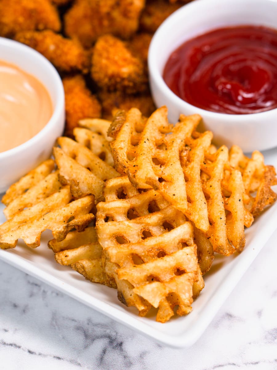 https://www.onehappyhousewife.com/wp-content/uploads/2022/05/air-fryer-waffle-fries-on-a-plate-with-chicken-nuggets-4-900x1200.jpg