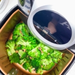 shaking and tossing broccoli in the air fryer before completing the roasting