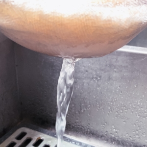 clear water draining from rice while rinsing in a mesh strainer