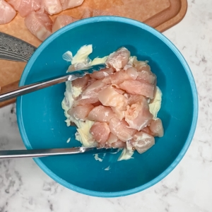 combining chicken with mayonnaise in a mixing bowl