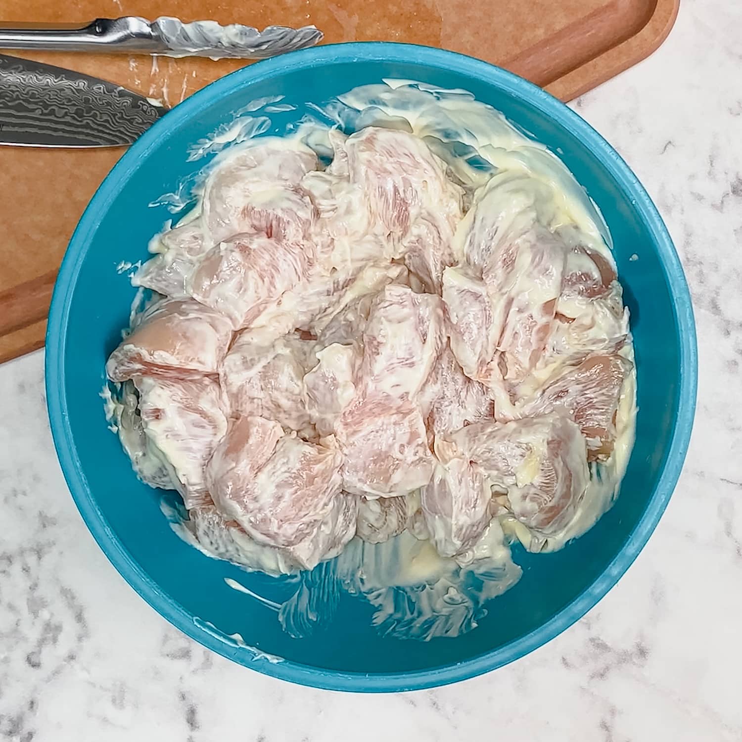 cubed chicken combined with mayonnaise in a mixing bowl