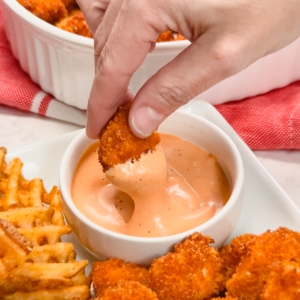 dipping a chicken nugget in pink sauce