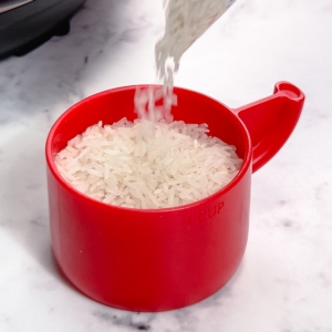 filling a measuring cup with jasmine rice