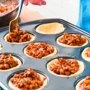 filling cornbread cups with a sloppy joe mixture