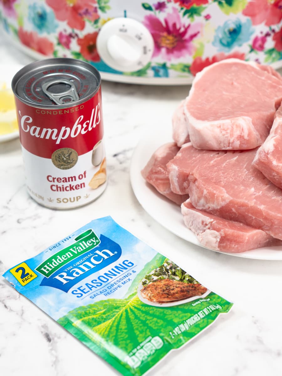 ingredients for slow cooker ranch pork chops including pork chops, a ranch packet, a can of cream of chicken soup, and butter