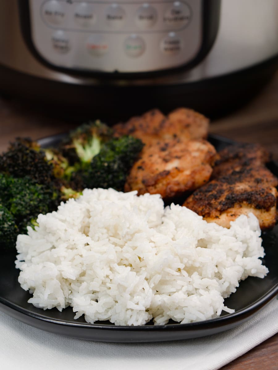 jasmine rice on a plate with chicken and broccoli and the instant pot in the background