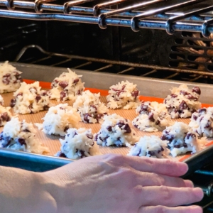 placing a baking sheet of chocolate chip coconut macaroons in the oven