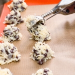 placing a scoop of chocolate chip coconut macaroon on a baking sheet