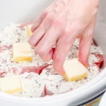 placing slices of butter over ranch seasoned pork chops in the slow cooker