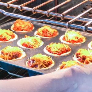 placing sloppy joe cornbread cups into the oven