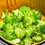 seasoned broccoli in the air fryer basket before roasting