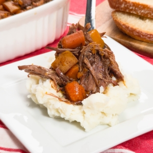 serving slow cooker pot roast over mashed potatoes