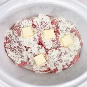 slices of butter and ranch seasoning over pork chops in the slow cooker