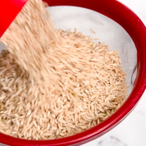 adding brown rice to a mesh strainer