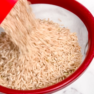 adding brown rice to a mesh strainer