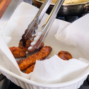 adding gluten free chicken tenders to a paper towel lined serving dish