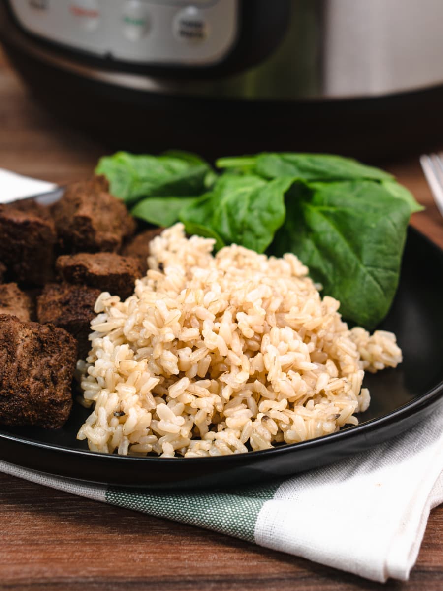 instant pot brown rice on a plate with beef and spinach