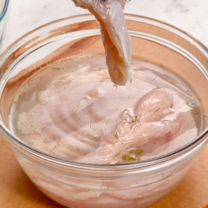 removing a tender from pickle juice marinade and shaking off excess juice