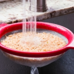 rinsing brown rice in a mesh strainer