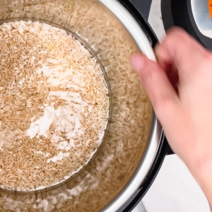 twisting and agitating the pressure cooker liner to mix the ingredients for making brown rice