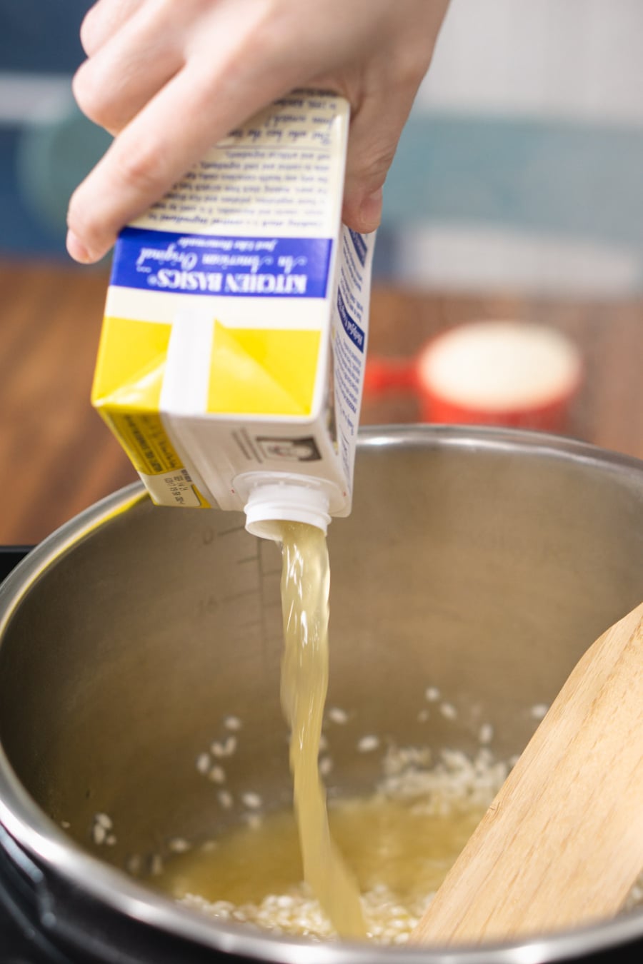 pouring chicken stock into the Instant Pot to make risotto