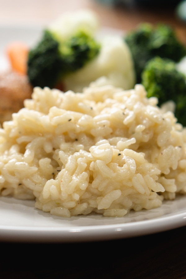 parmesan risotto served on a plate as a side to chicken thighs and broccoli