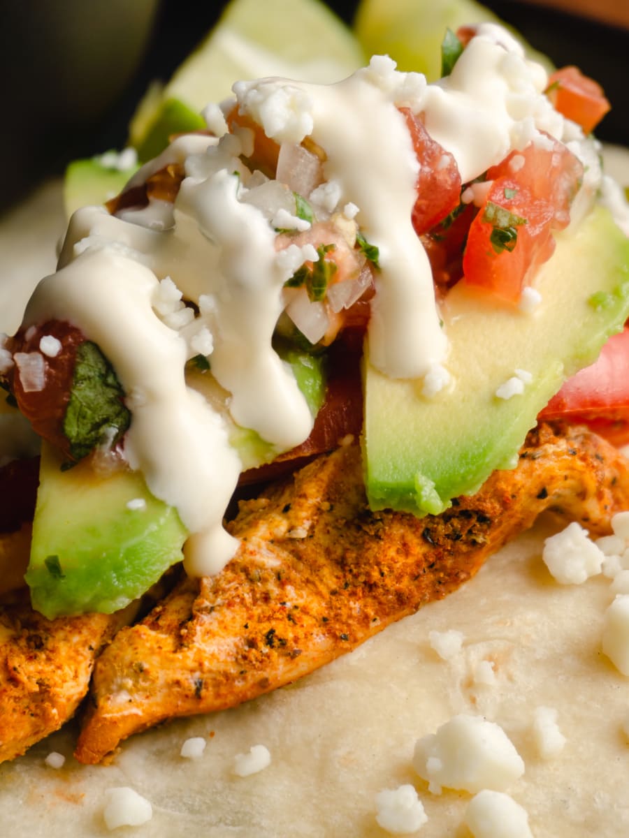 close up of sheet pan chicken fajitas with honduran crema drizzled on top