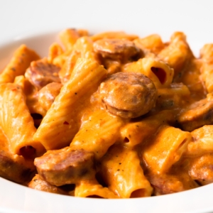 a bowl of cream cheese pasta made with rigatoni and sausage