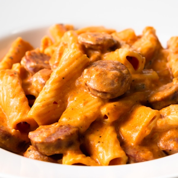 a bowl of cream cheese pasta made with rigatoni and sausage