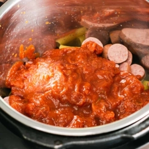 overhead view of the instant pot with marinara, pasta, and sausage layered inside for making cream cheese pasta with sausage