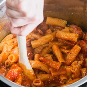 mixing the ingredients for cream cheese pasta with sausage in the instant pot