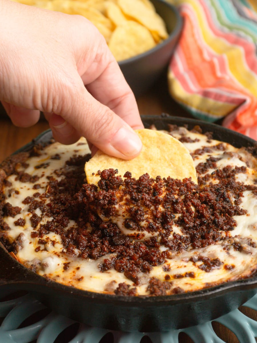 a skillet of refried beans, melted cheese, and crumbled chorizo