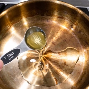 adding a tablespoon of oil to a frying pan