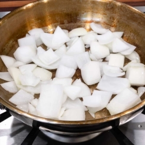 adding cut onion to frying pan