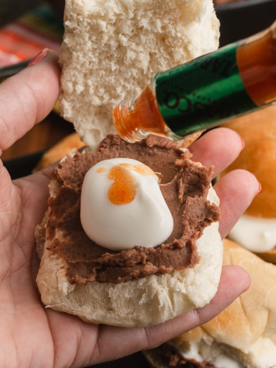 pan con frijoles or bread with beans being drizzled with hot sauce