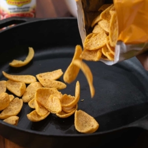 pouring fritos corn chips into a large skillet