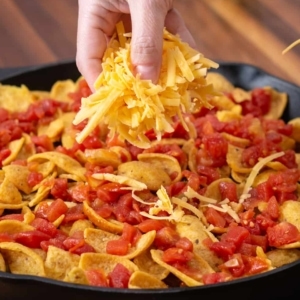 sprinkling shredded cheddar cheese on top of frito pie