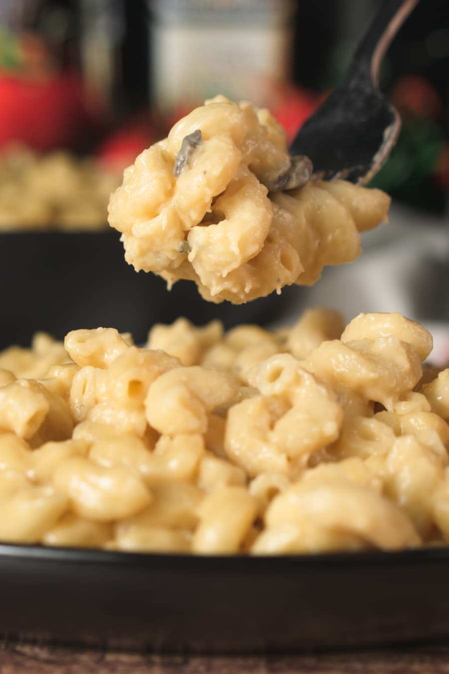 a bite of macaroni and cheese made with cream of mushroom soup on a fork being held over a plate full of the pasta